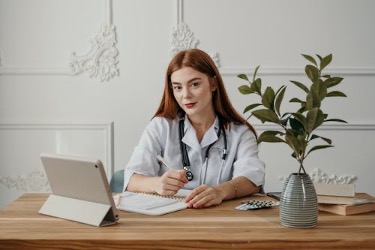 Doctor writing a note to certify a patient’s need for sick leave.