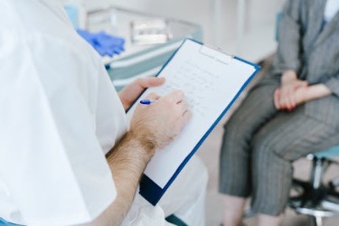 Doctor writing a certified note for a patient to take time off work for illness.