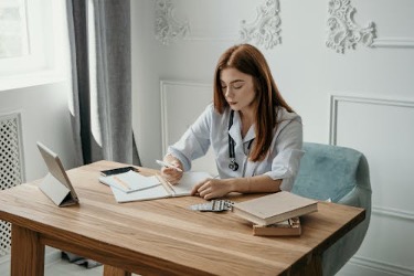 Doctor writing a note in a notebook to support a patient's sick leave needs.